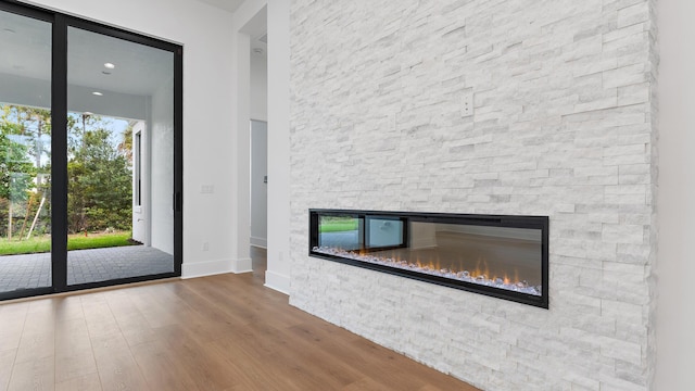 13250 Artisan Cir, Palm Beach Gardens, FL 33418 - unfurnished living room featuring a stone fireplace and wood finished floors