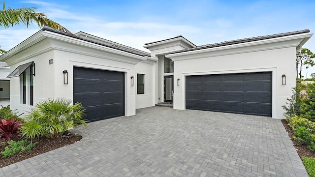 13250 Artisan Cir, Palm Beach Gardens, FL 33418 - view of front of house with an attached garage, stucco siding, and decorative driveway
