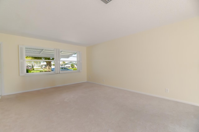 unfurnished room with light carpet and baseboards