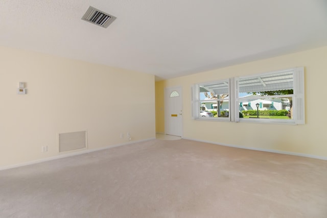 unfurnished room featuring light carpet and baseboards