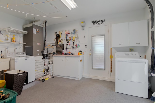 clothes washing area featuring washer and clothes dryer, cabinet space, light colored carpet, and heating unit