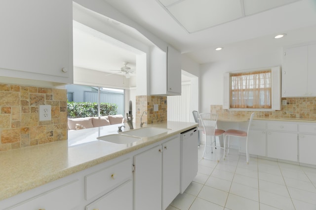 kitchen featuring white dishwasher, a sink, decorative backsplash, light countertops, and light tile patterned flooring