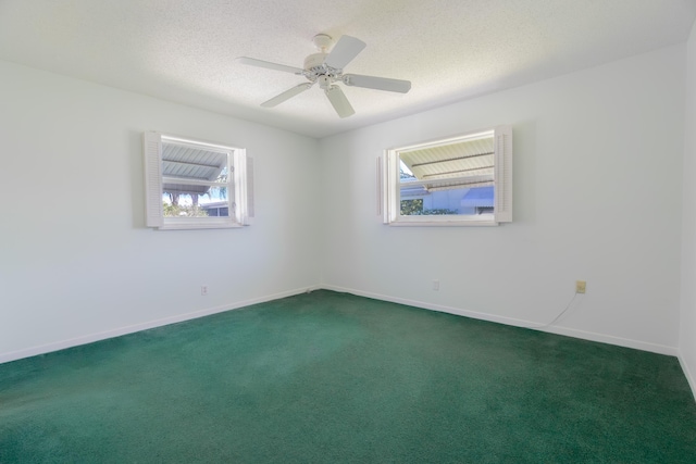 spare room featuring healthy amount of natural light, dark colored carpet, baseboards, and a textured ceiling