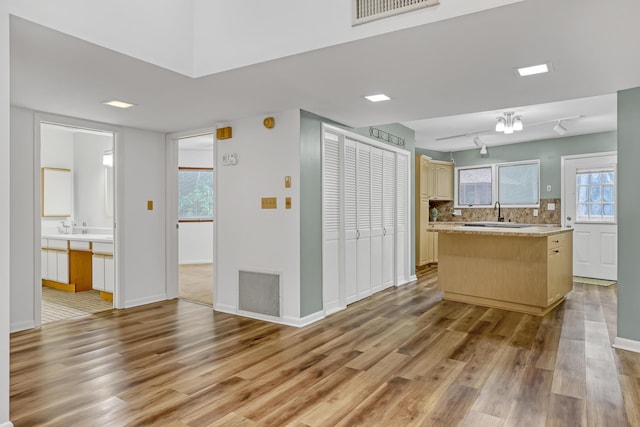 1130 Melinda Ln, Haverhill, FL 33417 - kitchen with light wood-type flooring, light countertops, a sink, backsplash, and baseboards