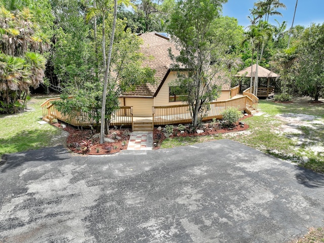 1130 Melinda Ln, Haverhill, FL 33417 - view of property exterior with a wooden deck, roof with shingles, view of scattered trees, and a yard