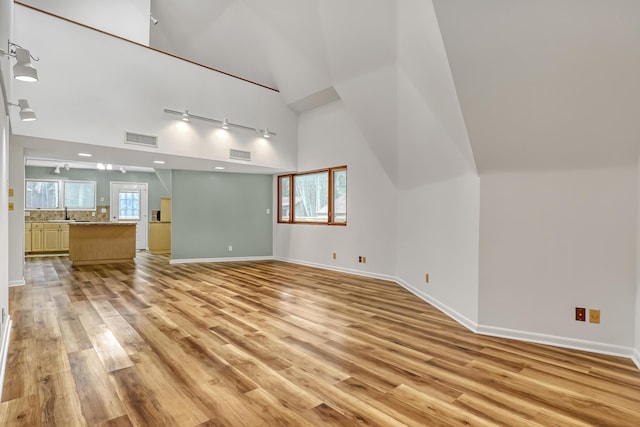1130 Melinda Ln, Haverhill, FL 33417 - unfurnished living room featuring track lighting, high vaulted ceiling, light wood-style floors, and baseboards