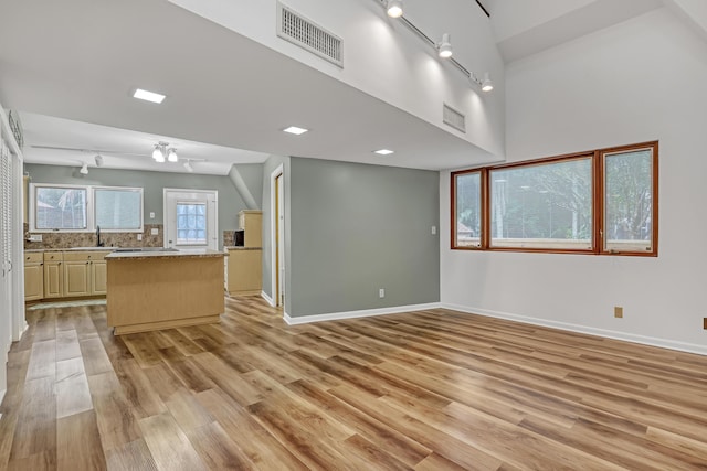 1130 Melinda Ln, Haverhill, FL 33417 - unfurnished living room with track lighting, light wood finished floors, baseboards, a sink, and a high ceiling