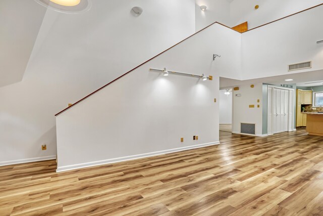 1130 Melinda Ln, Haverhill, FL 33417 - unfurnished living room featuring light wood-type flooring, baseboards, and a high ceiling