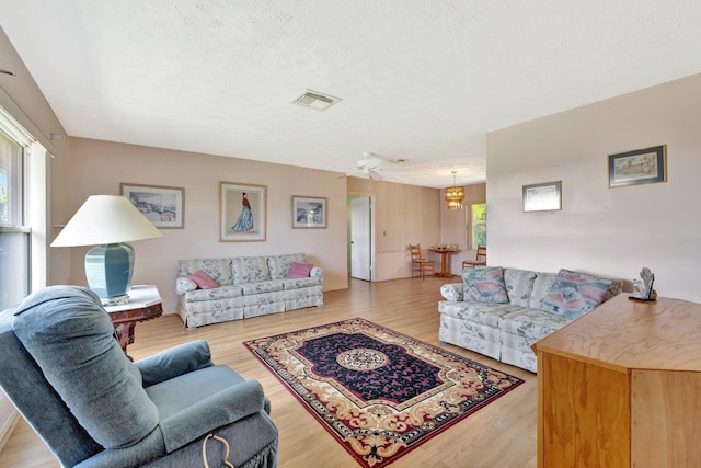 472 SW Aster Rd, Port Saint Lucie, FL 34953 - living room featuring wood finished floors, a chandelier, a textured ceiling, and ceiling fan