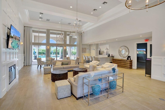 11354 Mainsail Ct, Wellington, FL 33449 - living area with a chandelier, a high ceiling, crown molding, light wood-style floors, and a glass covered fireplace
