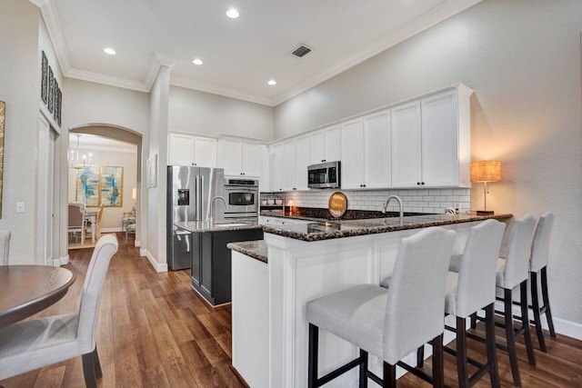 11354 Mainsail Ct, Wellington, FL 33449 - kitchen featuring appliances with stainless steel finishes, dark stone counters, ornamental molding, white cabinetry, and a peninsula
