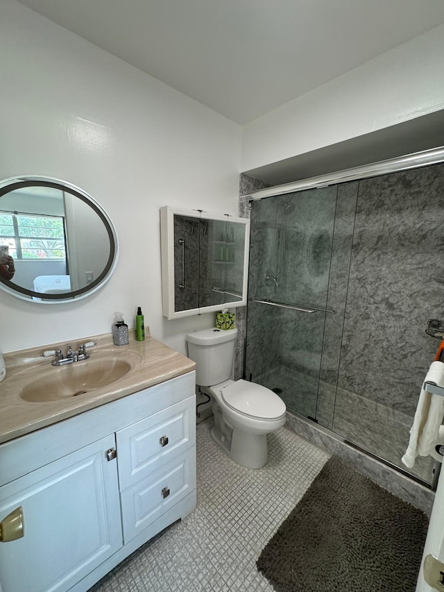 bathroom with a shower stall, toilet, vanity, and tile patterned floors