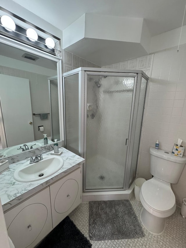 full bathroom featuring a stall shower, vanity, toilet, tile patterned floors, and tile walls