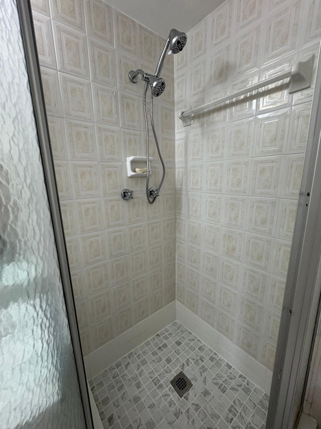 bathroom with a shower stall, baseboards, tile patterned flooring, and wallpapered walls