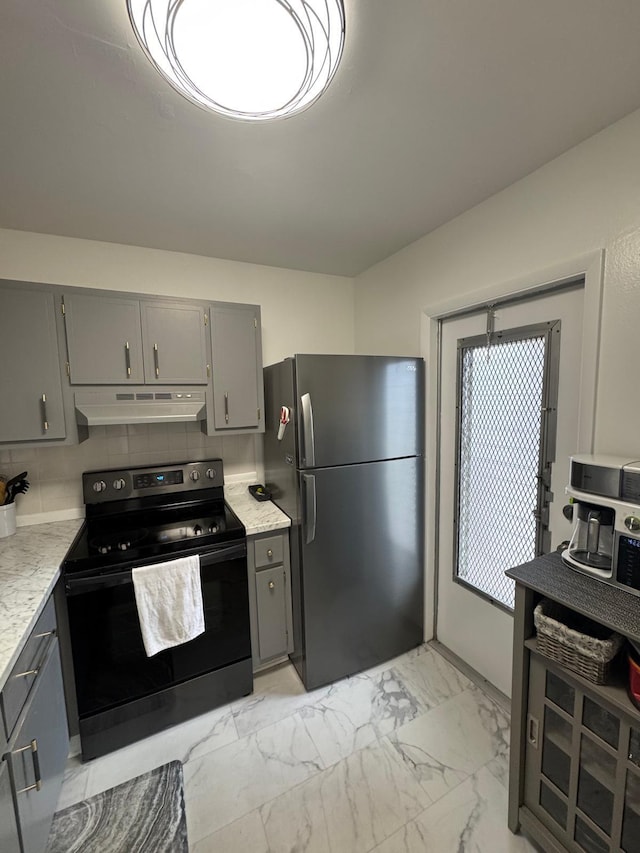 kitchen featuring black electric range, freestanding refrigerator, gray cabinetry, under cabinet range hood, and light marble finish flooring