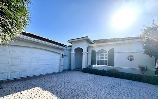 ranch-style home featuring decorative driveway, an attached garage, and stucco siding