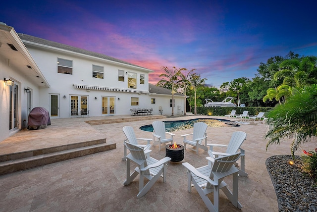 17736 103rd Ter N, Jupiter, FL 33478 - pool at dusk with an outdoor fire pit, french doors, and a patio area