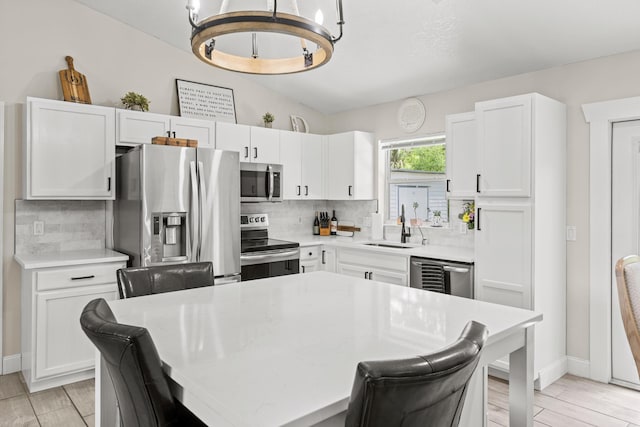 6905 Bayard Rd, Fort Pierce, FL 34951 - kitchen featuring appliances with stainless steel finishes, backsplash, white cabinets, and a chandelier