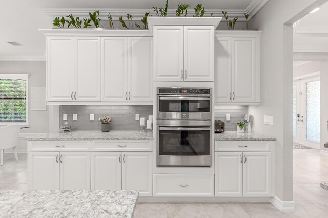 5211 SW Blue Daze Way, Palm City, FL 34990 - kitchen with stainless steel double oven, backsplash, white cabinets, light stone counters, and light tile patterned floors
