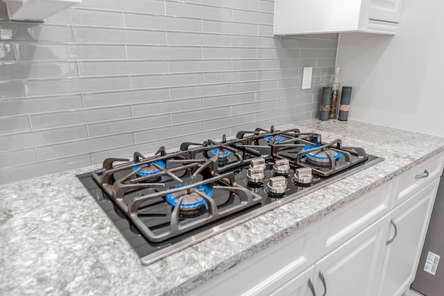 5211 SW Blue Daze Way, Palm City, FL 34990 - kitchen view of black gas cooktop, tasteful backsplash, white cabinetry, and light stone counters