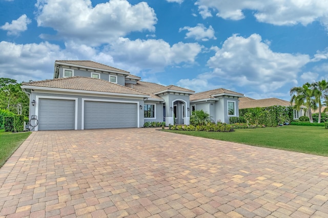 5211 SW Blue Daze Way, Palm City, FL 34990 - mediterranean / spanish home featuring stucco siding, an attached garage, a front lawn, decorative driveway, and a tile roof
