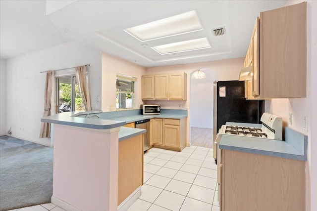 531 SE Evergreen Ter, Port Saint Lucie, FL 34983 - kitchen with light brown cabinetry, stainless steel dishwasher, a peninsula, light tile patterned flooring, and light countertops
