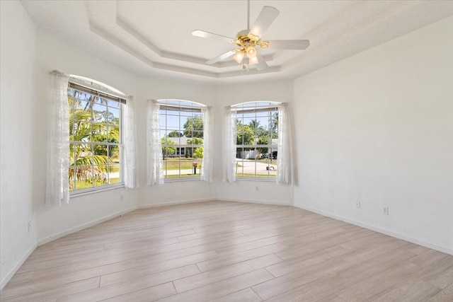 531 SE Evergreen Ter, Port Saint Lucie, FL 34983 - spare room with a tray ceiling, light wood-type flooring, a ceiling fan, and baseboards