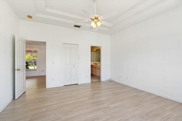 531 SE Evergreen Ter, Port Saint Lucie, FL 34983 - unfurnished bedroom with a raised ceiling, light wood finished floors, baseboards, ensuite bathroom, and a towering ceiling