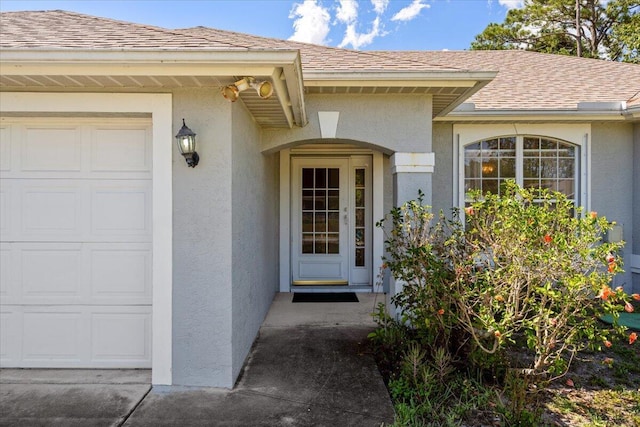 531 SE Evergreen Ter, Port Saint Lucie, FL 34983 - view of exterior entry with an attached garage, stucco siding, and a shingled roof