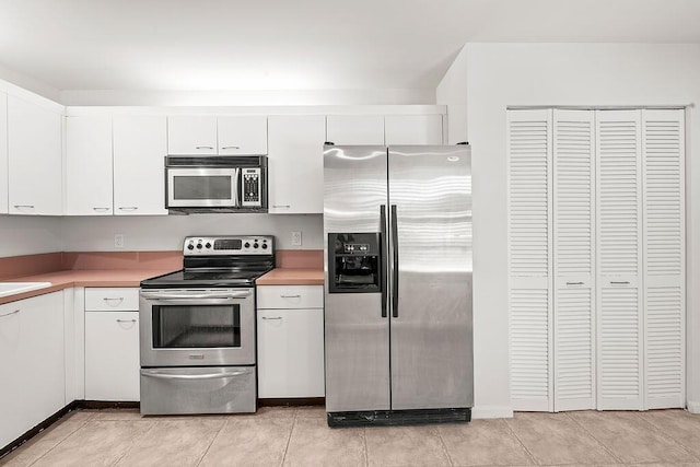 kitchen with stainless steel appliances, white cabinets, light countertops, and light tile patterned floors