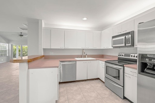 kitchen featuring appliances with stainless steel finishes, a peninsula, a sink, light countertops, and recessed lighting