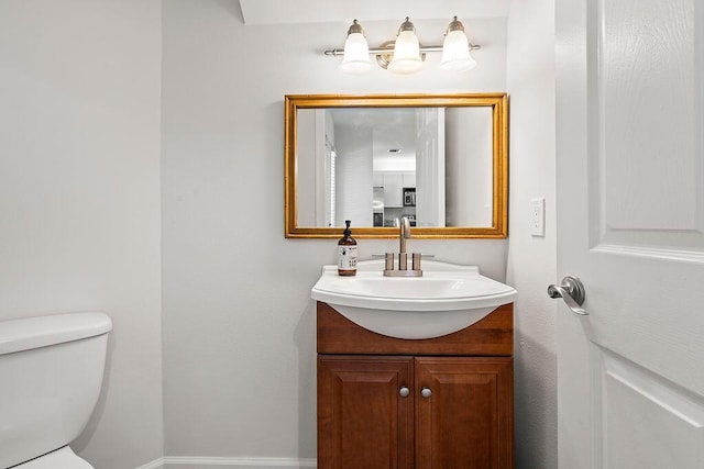 bathroom featuring toilet, vanity, and baseboards