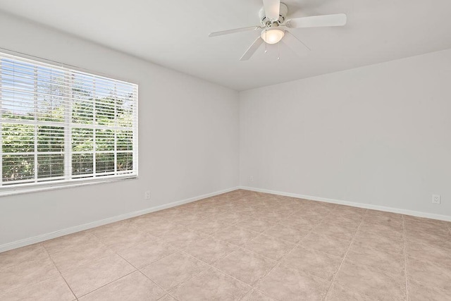 spare room with ceiling fan and baseboards