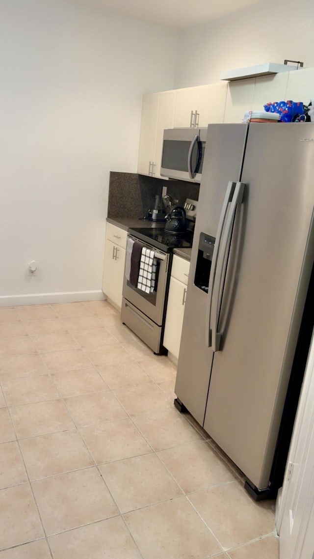 3608 Shoma Dr, Royal Palm Beach, FL 33414 - kitchen with stainless steel appliances, light tile patterned flooring, white cabinets, and dark countertops