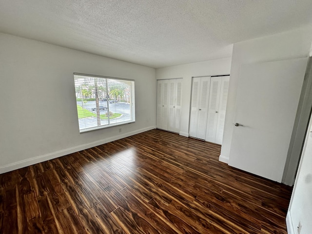 815 W Boynton Beach Blvd Unit 8-204, Boynton Beach, FL 33426 - unfurnished bedroom with multiple closets, dark wood-type flooring, a textured ceiling, and baseboards