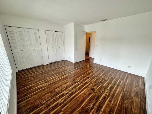 815 W Boynton Beach Blvd Unit 8-204, Boynton Beach, FL 33426 - unfurnished bedroom featuring dark wood finished floors, multiple closets, and baseboards