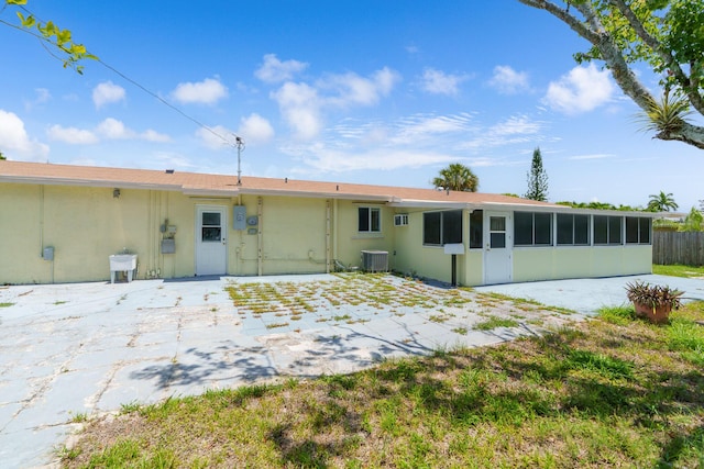 rear view of house with a sunroom, cooling unit, stucco siding, a patio area, and fence
