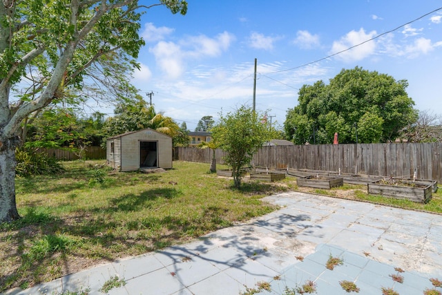 view of yard with a vegetable garden, a storage unit, a patio area, and an outbuilding