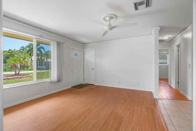 empty room with ornamental molding, light wood-style flooring, a ceiling fan, and baseboards