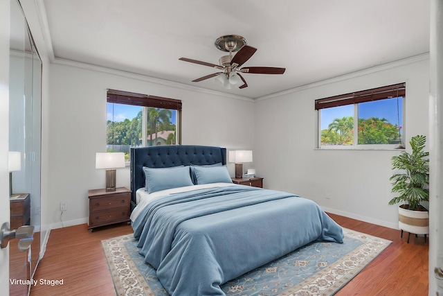 bedroom featuring multiple windows, ornamental molding, baseboards, and wood finished floors