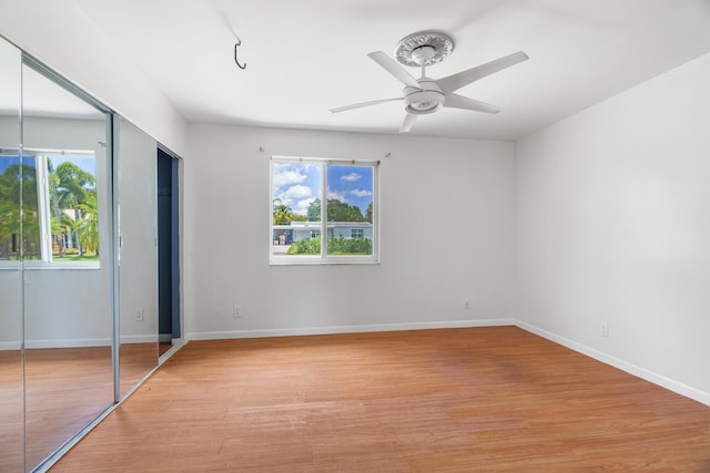 unfurnished bedroom featuring multiple windows, light wood finished floors, baseboards, and ceiling fan
