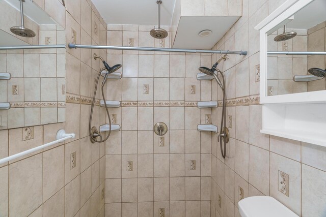 bathroom featuring tiled shower and toilet
