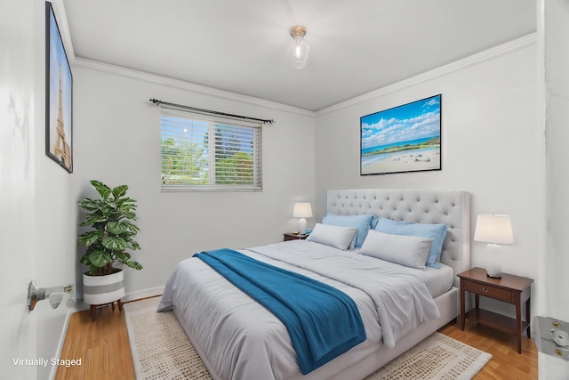 bedroom featuring ornamental molding, light wood-style floors, and baseboards