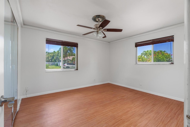 empty room featuring ornamental molding, ceiling fan, wood finished floors, and baseboards