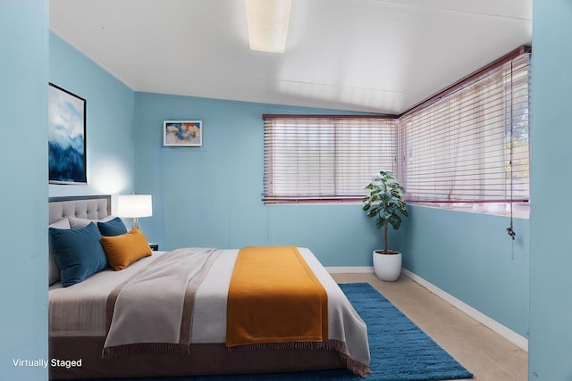 bedroom with tile patterned flooring, baseboards, and lofted ceiling