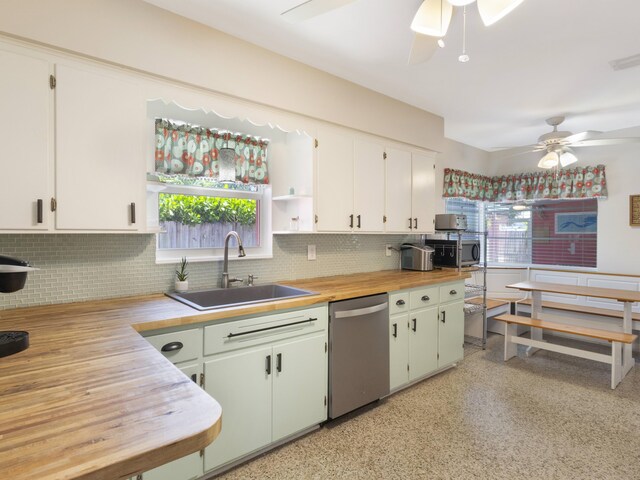 1001 N Lakeside Dr, Lake Worth Beach, FL 33460 - kitchen with stainless steel dishwasher, ceiling fan, a sink, and decorative backsplash
