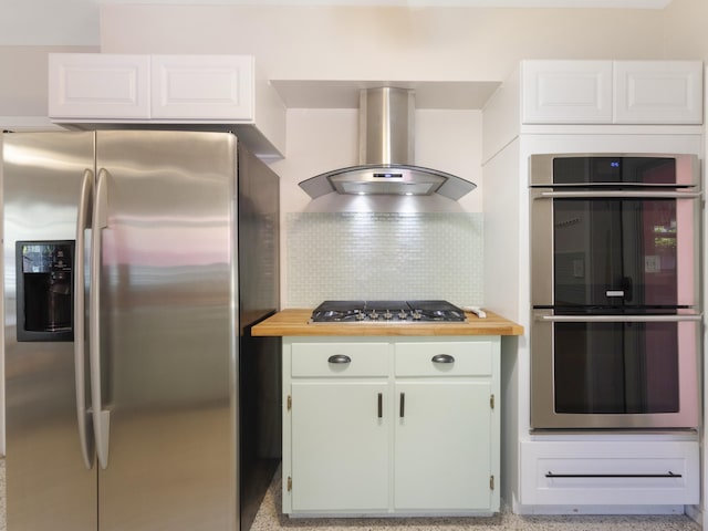 1001 N Lakeside Dr, Lake Worth Beach, FL 33460 - kitchen featuring appliances with stainless steel finishes, wall chimney range hood, butcher block countertops, decorative backsplash, and white cabinets