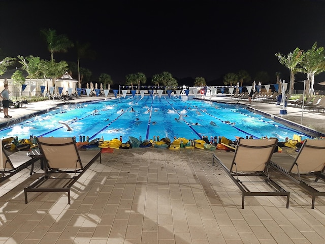 pool at night with a patio area and a community pool