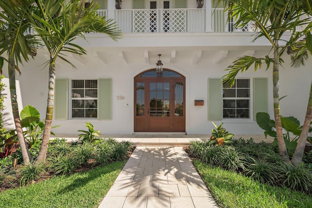 entrance to property featuring a balcony and stucco siding
