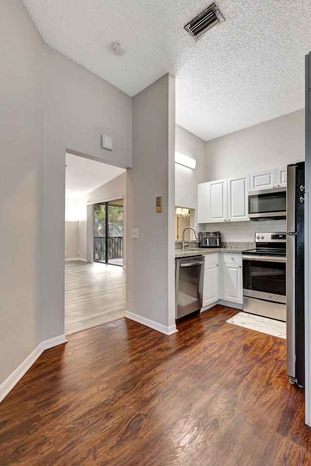 5450 Verona Dr Unit L, Boynton Beach, FL 33437 - kitchen with appliances with stainless steel finishes, dark wood finished floors, baseboards, white cabinetry, and a textured ceiling